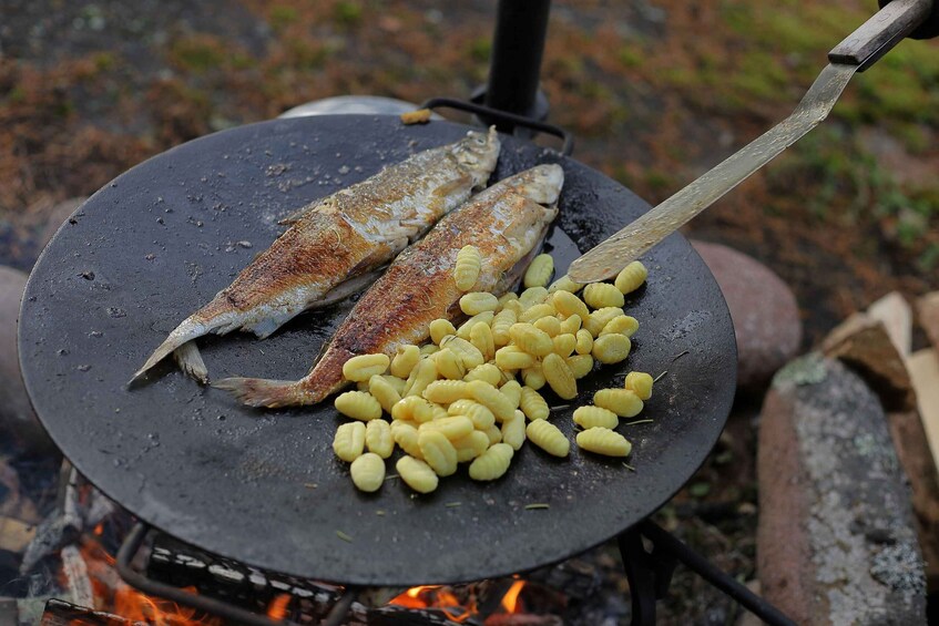Two fish and a pile of corn on a grill over an open fire. 2
