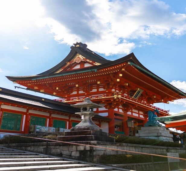 A traditional Japanese temple with a prominent red and gold structure, a stone lantern, and a statue of a deity. 4