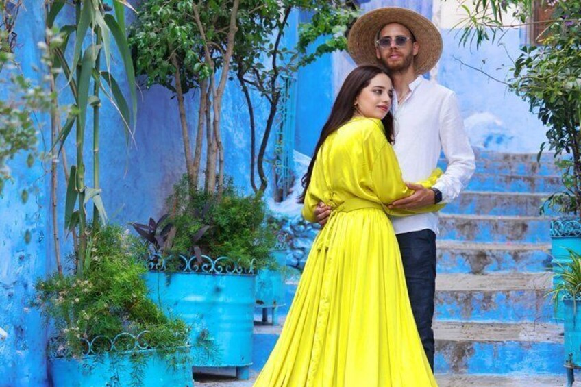 A couple embracing in front of a blue wall with steps and greenery. 5