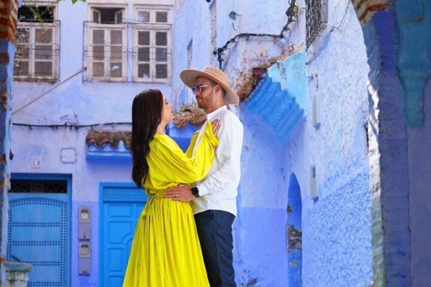 A couple embracing in a narrow alleyway with blue doors and white walls. 2