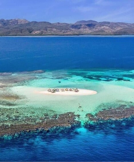 A clear blue sea with a small island with structures. 2