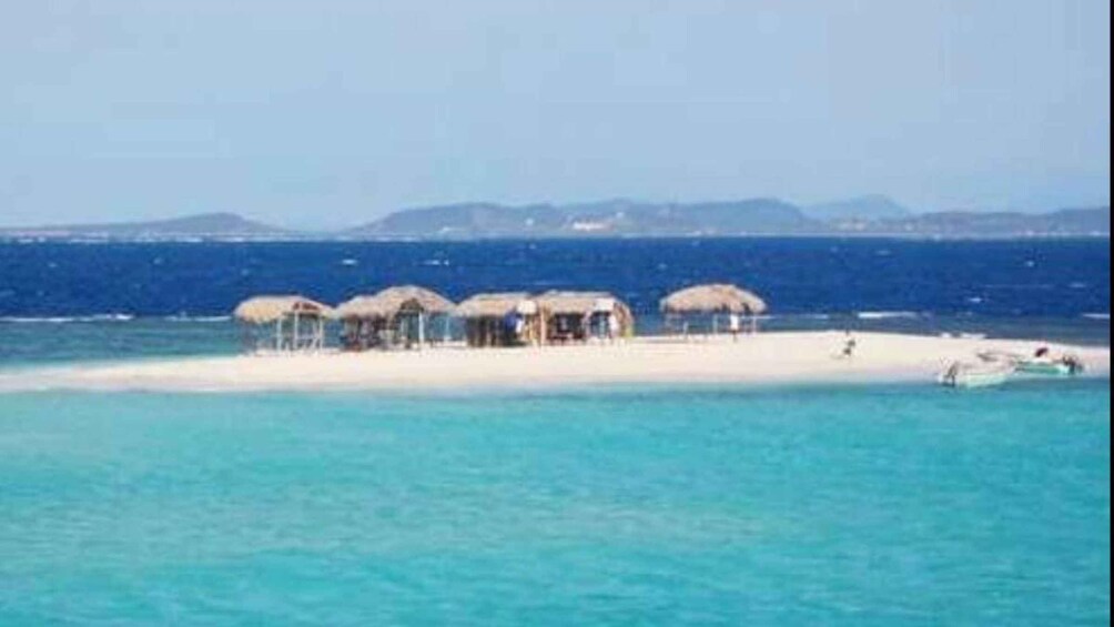 A beach with thatched-roof huts and a clear blue sea. 5