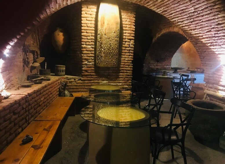 A rustic brick interior with a central circular stone basin, wooden benches, and a brick oven. 3