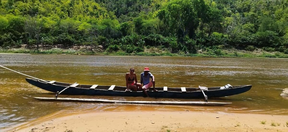 Two people in a canoe on a river with a forested shoreline. 4
