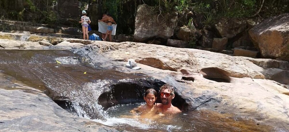 Two people in a natural water feature surrounded by rocks. 5