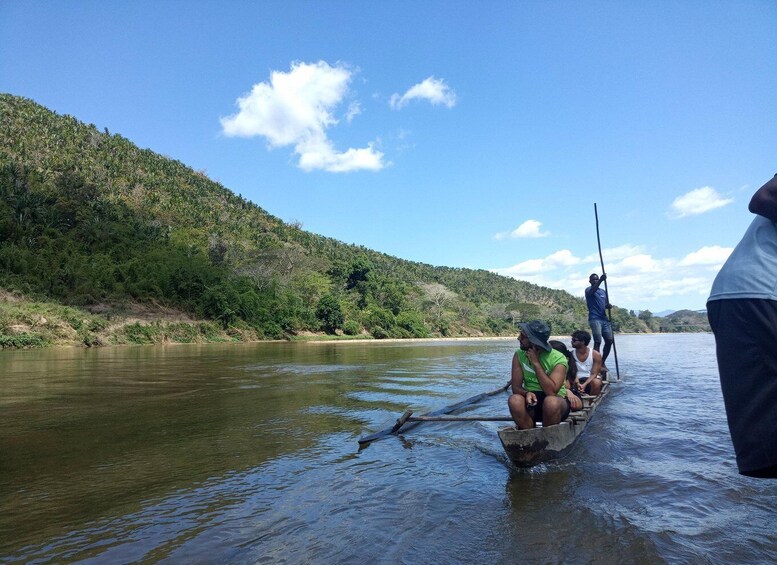 People on a boat in a river with a forested hillside in the background. 1