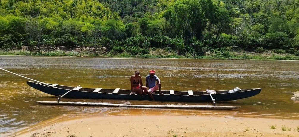 A river with two people in a canoe, surrounded by greenery. 2