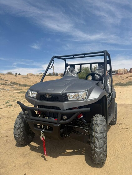 A Kymco ATV parked on sandy terrain with a clear sky. 5