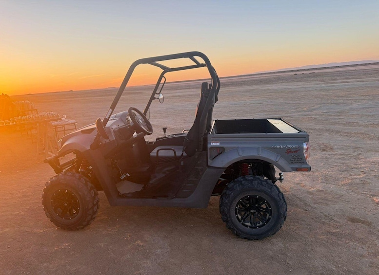 A utility vehicle parked on a desert landscape during sunset. 2