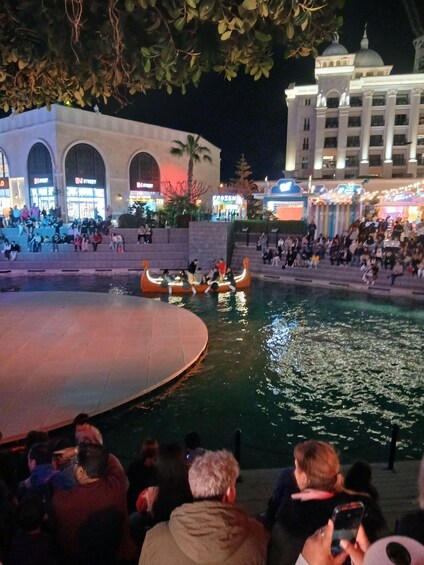 A nighttime outdoor event with a water stage and audience. 5