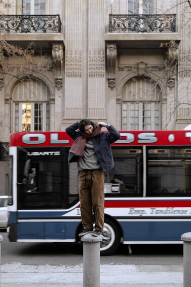 A person standing on a pole with a bus in the background. 5