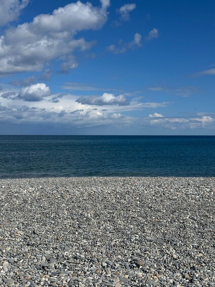 A pebbled beach with a clear sky and calm sea. 5