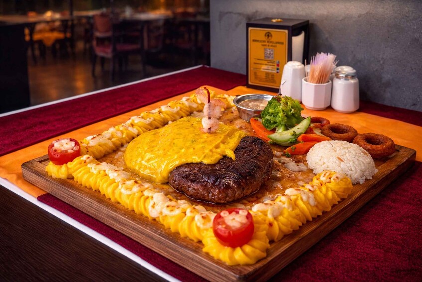 A large platter with a steak, shrimp, and yellow sauce, accompanied by rice, vegetables, and onion rings. 3