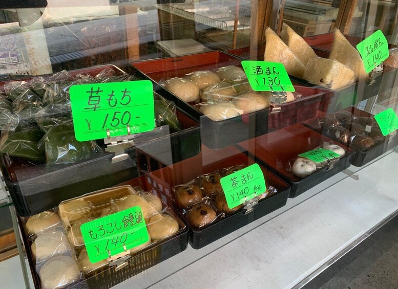 A variety of packaged food items displayed in a store window with price tags. 2