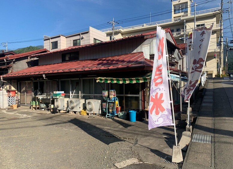 A storefront with a red roof, various fans, and a purple banner with Japanese characters. 4