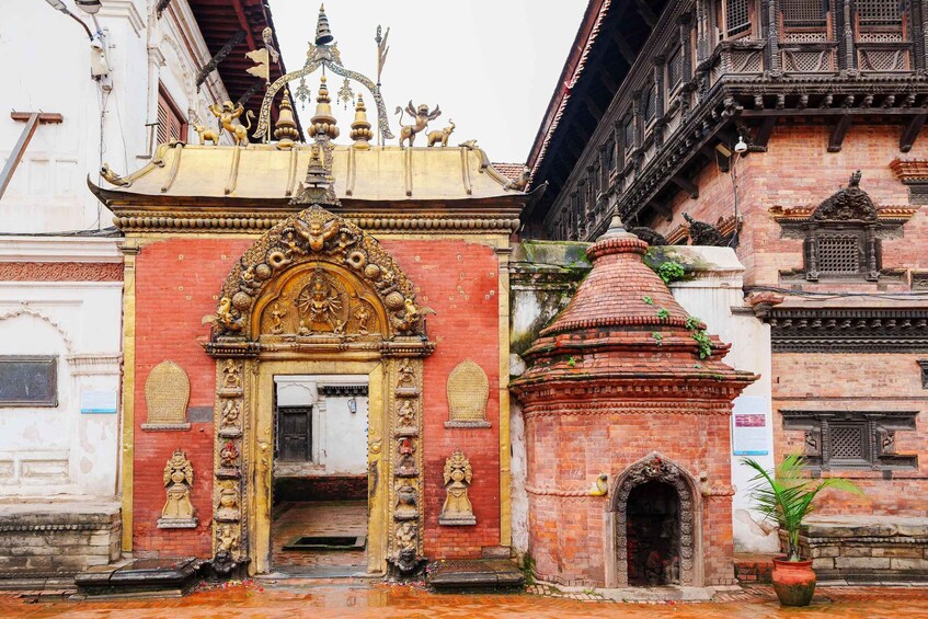 A temple entrance with ornate golden decorations and a red brick structure. 2