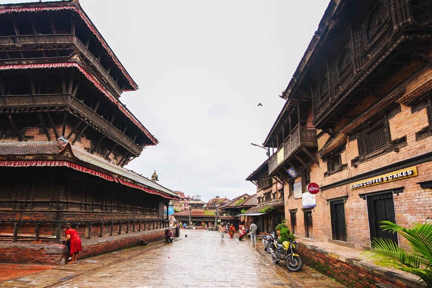 A traditional street with tiered buildings, a shop named 'Kings Coffee & Cakes,' and a person in a red dress. 3