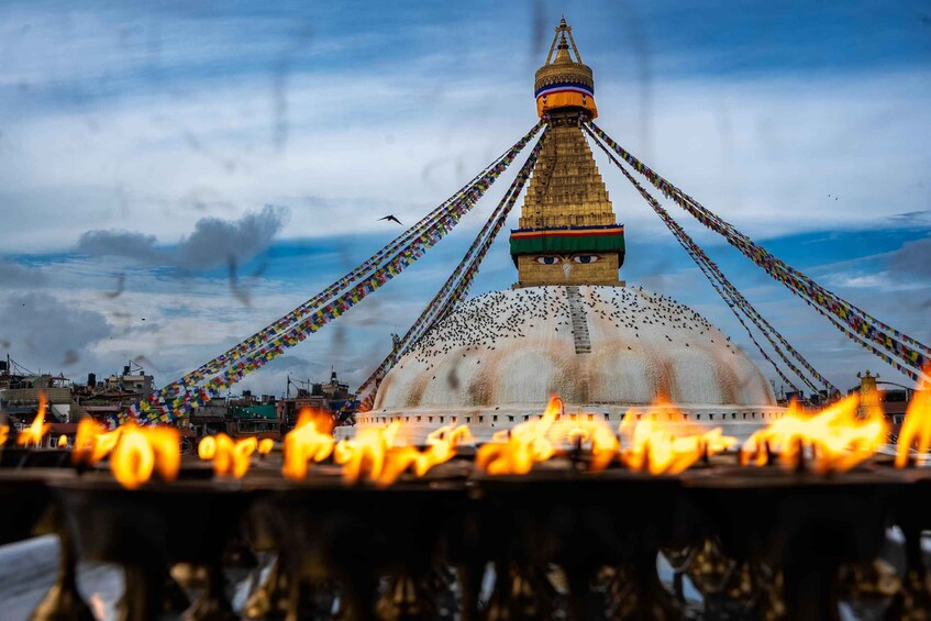 A stupa with prayer flags and flames in the foreground. 1