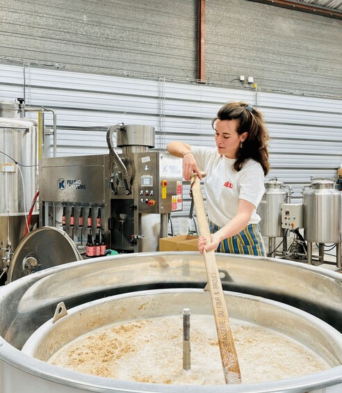 A person stirring a large industrial mixing tank in a brewery setting. 4