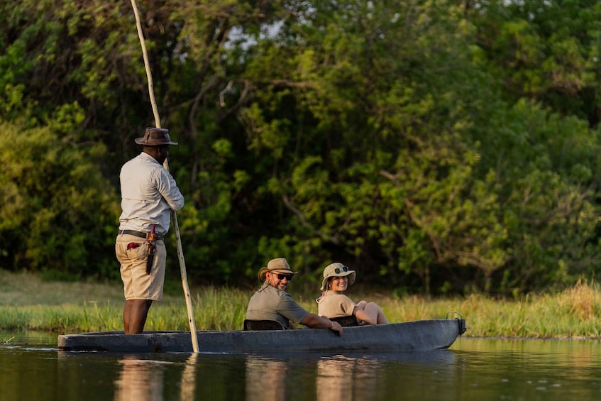 Two people in a boat on a calm river, surrounded by lush greenery. 1