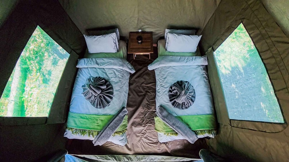A tent with two beds, each with a pillow and a small table. 5