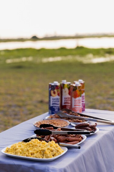A picnic table with food and juice boxes in an outdoor setting. 3