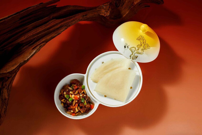A wooden branch, a bowl of food, and a covered dish with a yellow lid. 3