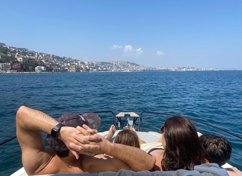 A boat with people holding hands, facing a coastal cityscape. 1