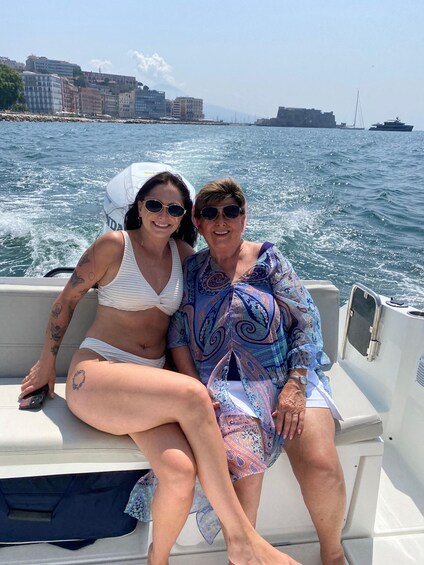 Two people on a boat with a cityscape and water in the background. 4
