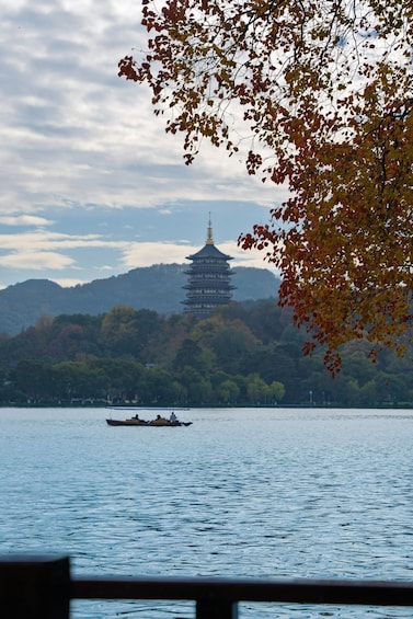 A pagoda on a hill, a boat on the water, and autumn leaves in the foreground. 2