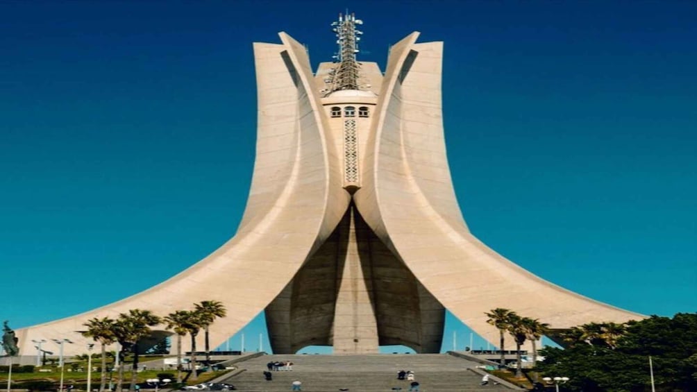 A modern architectural structure with a central tower and wide, curved wings. 1