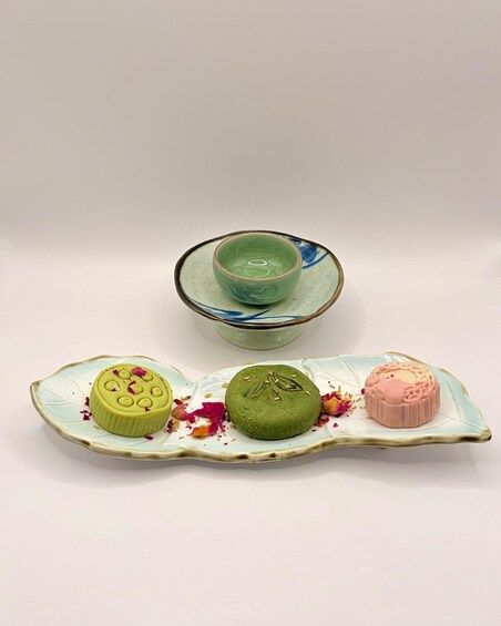 A ceramic plate with three mooncakes and a matching tea set. 2