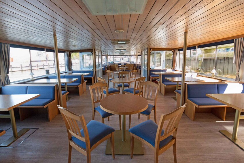 A restaurant with wooden tables and blue cushioned seating. 2