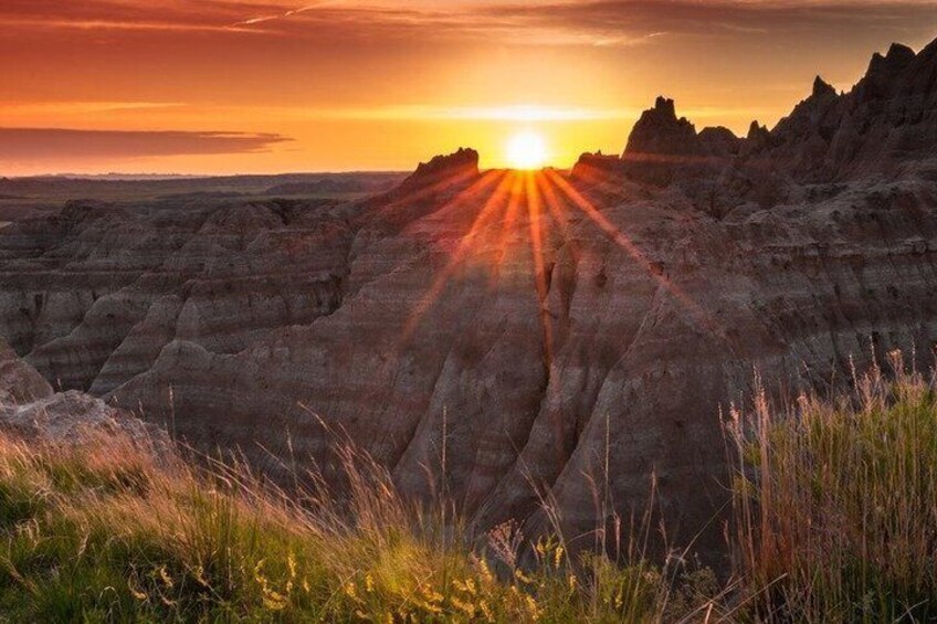 A sunset over a rugged landscape with distinct erosion patterns. 4
