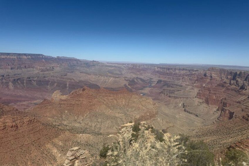 A vast canyon landscape with layered rock formations and sparse vegetation. 4