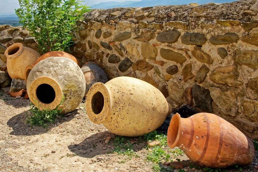 Ancient terracotta pots against a stone wall with a mountain view. 2