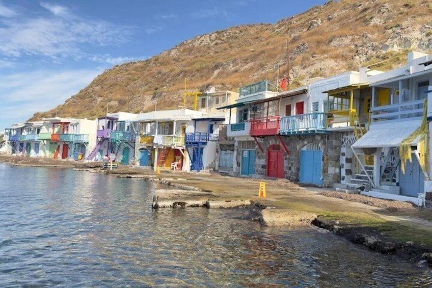 Colorful buildings by a waterfront with a rocky hillside in the background. 2