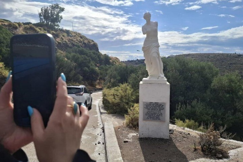 A person taking a photo of a statue with a car in the background. 3