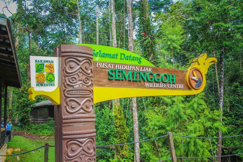A wooden signpost with 'Sarapak' and 'Wildlife Centre' text, surrounded by lush greenery. 2
