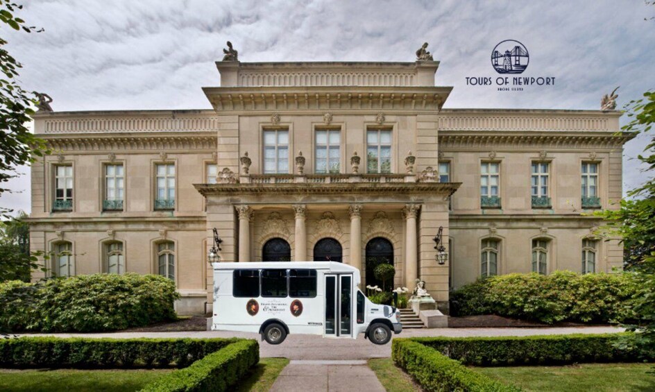 A large, classical building with a white bus in front, surrounded by well-manicured hedges. 4