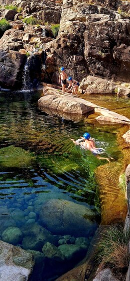 A natural pool with clear water, rocky edges, and a waterfall. 4
