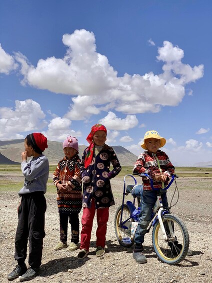 Four people standing on a gravel path with a mountain in the background. 3