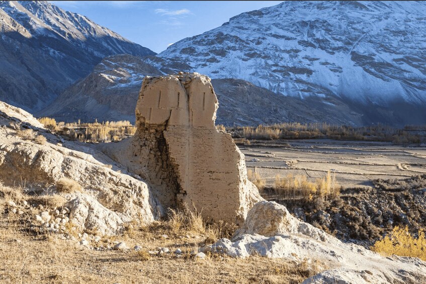 A mountainous landscape with a large rock formation in the foreground and snow-capped mountains in the background. 4