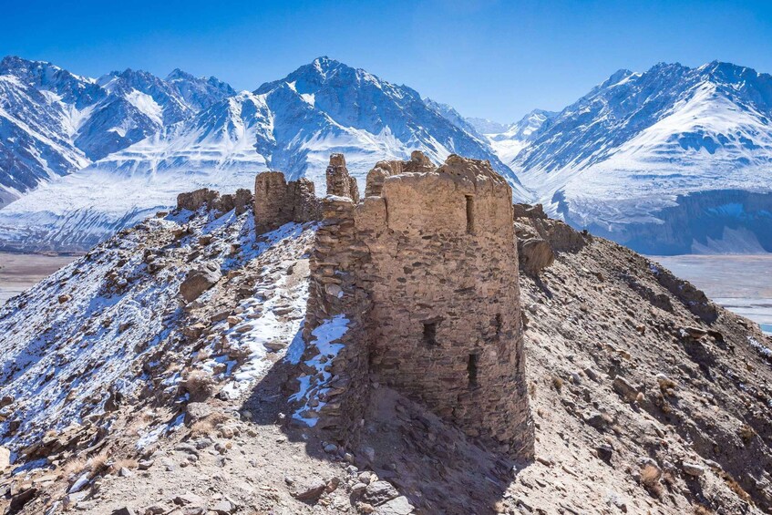 A snow-covered mountain with a ruined stone structure in the foreground. 5