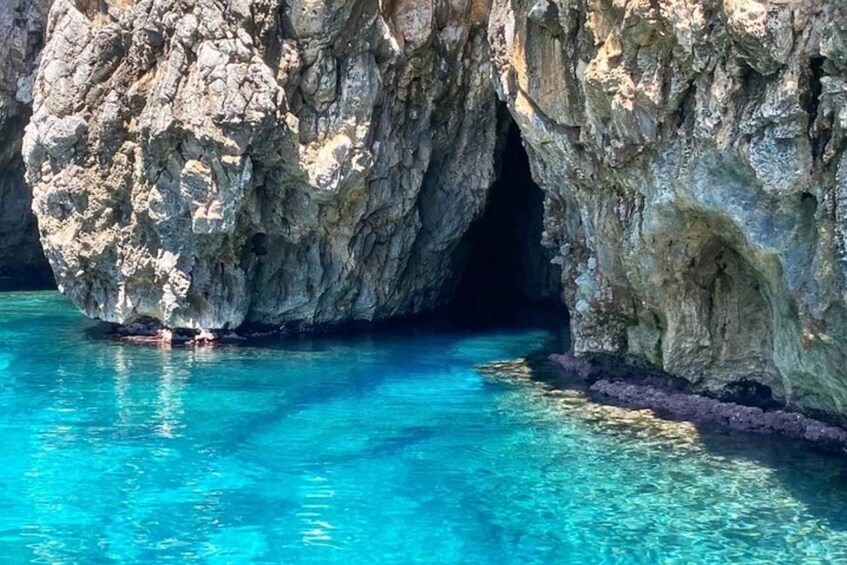 A rocky cave entrance with clear blue water. 2