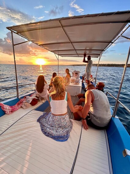 A group of people on a boat with a canopy, enjoying a sunset. 1