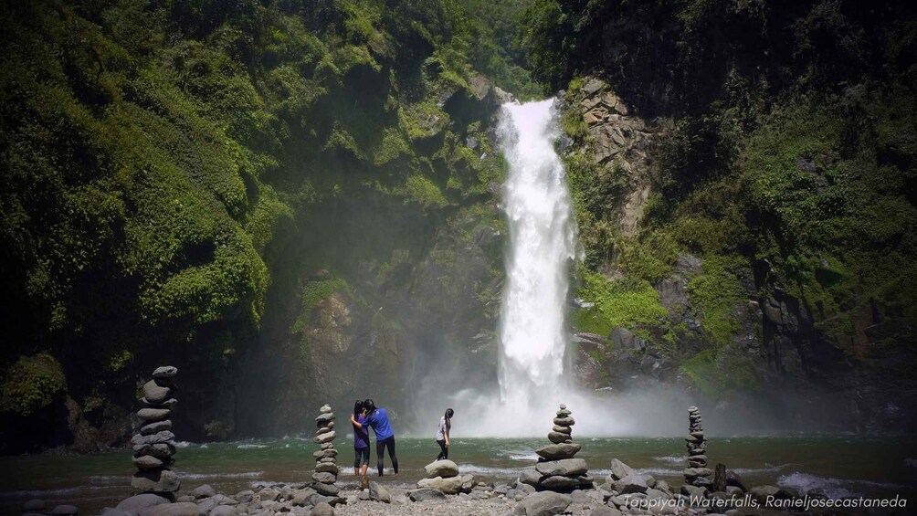 A waterfall, a river, and people standing by stacks of rocks. 3