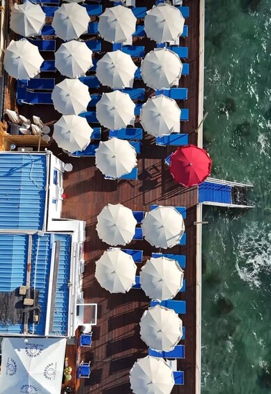 A deck with white umbrellas and blue chairs, overlooking a body of water. 1
