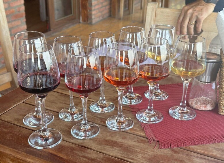 A wooden table with multiple wine glasses filled with different colored liquids. 3