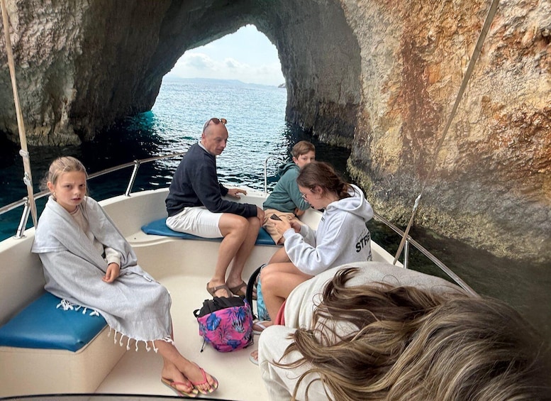 A group of people on a boat near a rocky coastline with a clear view of the sea. 3